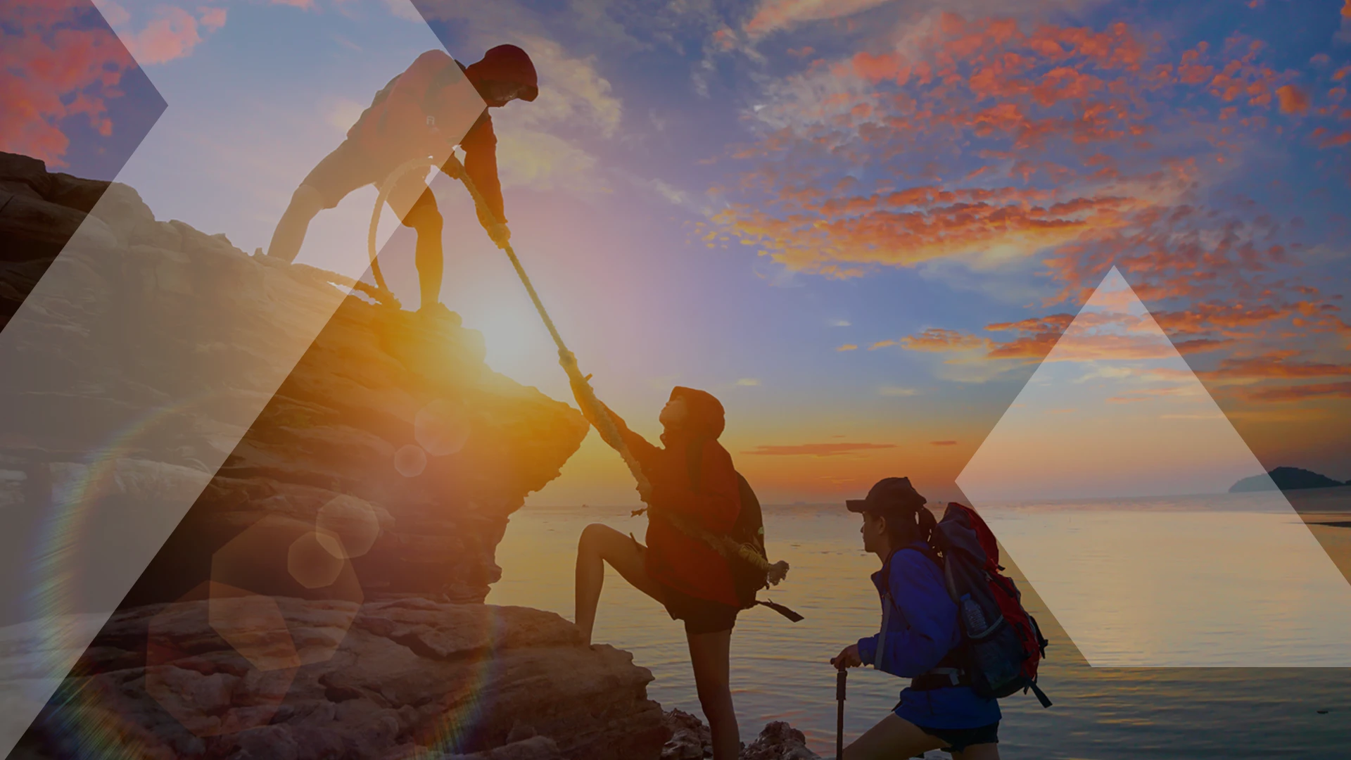 Three hikers at sunrise, with one hiker helping another climb a rocky hill while the third watches, symbolizing support and teamwork in scaling up